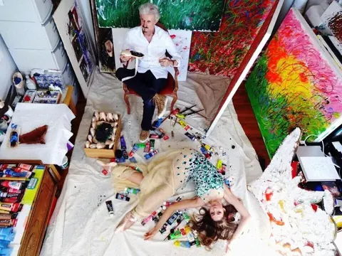Erzählung aus der Vogelperspektive in einem Künstleratelier mit Maler, Leinwänden, Werkzeugen und liegendem Modell; die dichte Komposition dokumentiert kreativen Prozess…