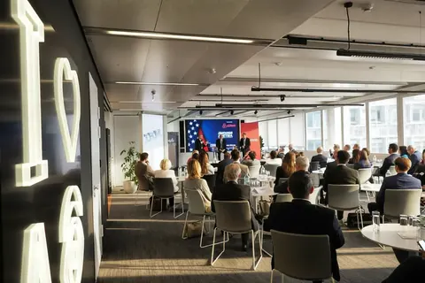 Weite Establishing-Aufnahme einer Wirtschaftskonferenz in einem modernen Veranstaltungsort mit Publikum, Bühne, Präsentationsfläche und räumlichem Verhältnis des Events.