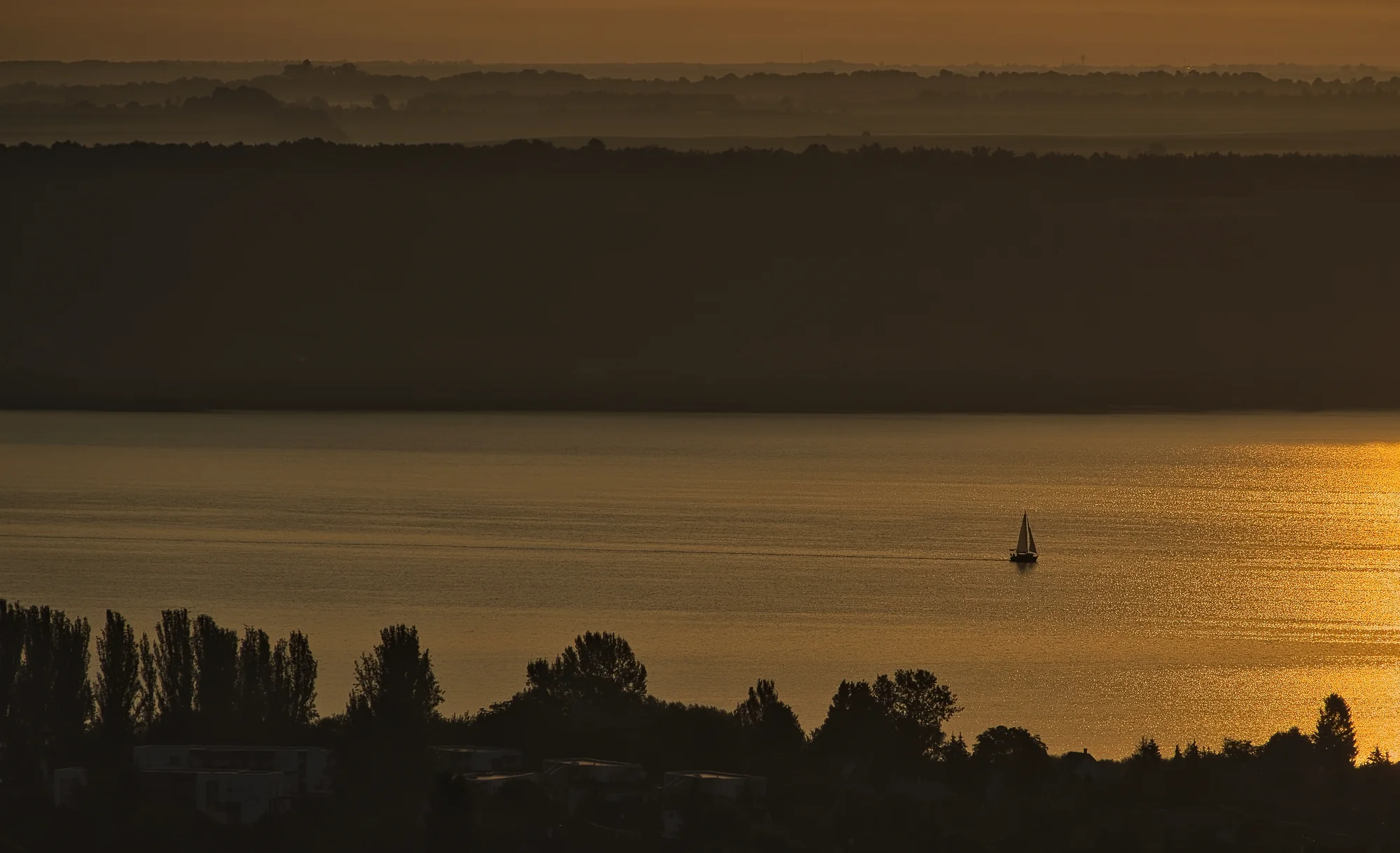 Minimalistische Sonnenuntergangslandschaft mit ferner Silhouette über dem Wasser