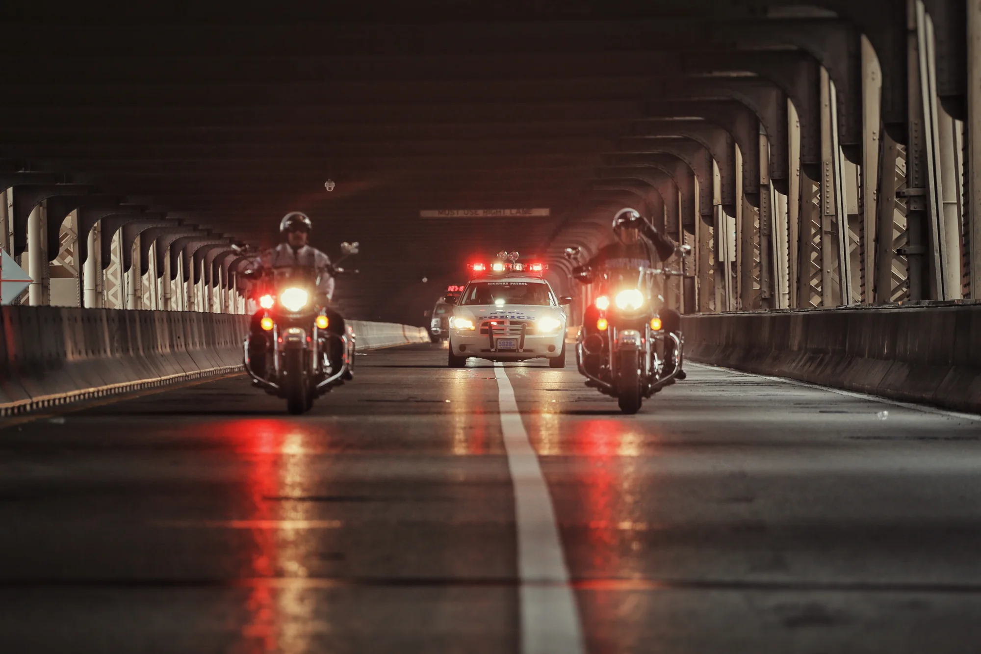 Polizeimotorräder und Fahrzeuge nachts unter einer Brücke